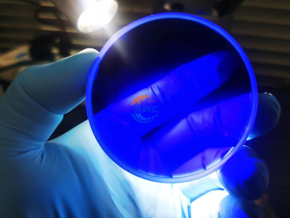 Blue transparent sapphire disc held under light for visual inspection